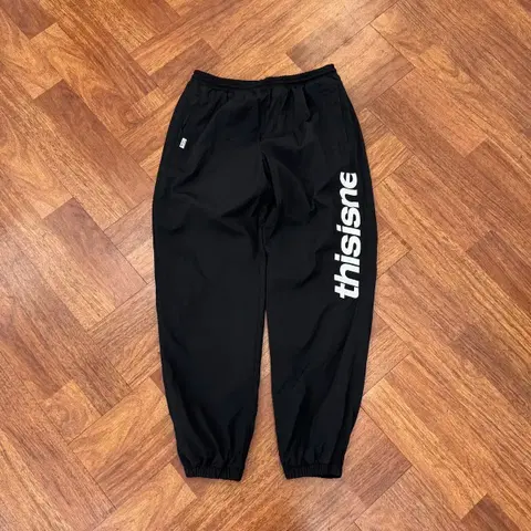 L 디스이즈네버댓 블랙 자수로고 나일론 팬츠